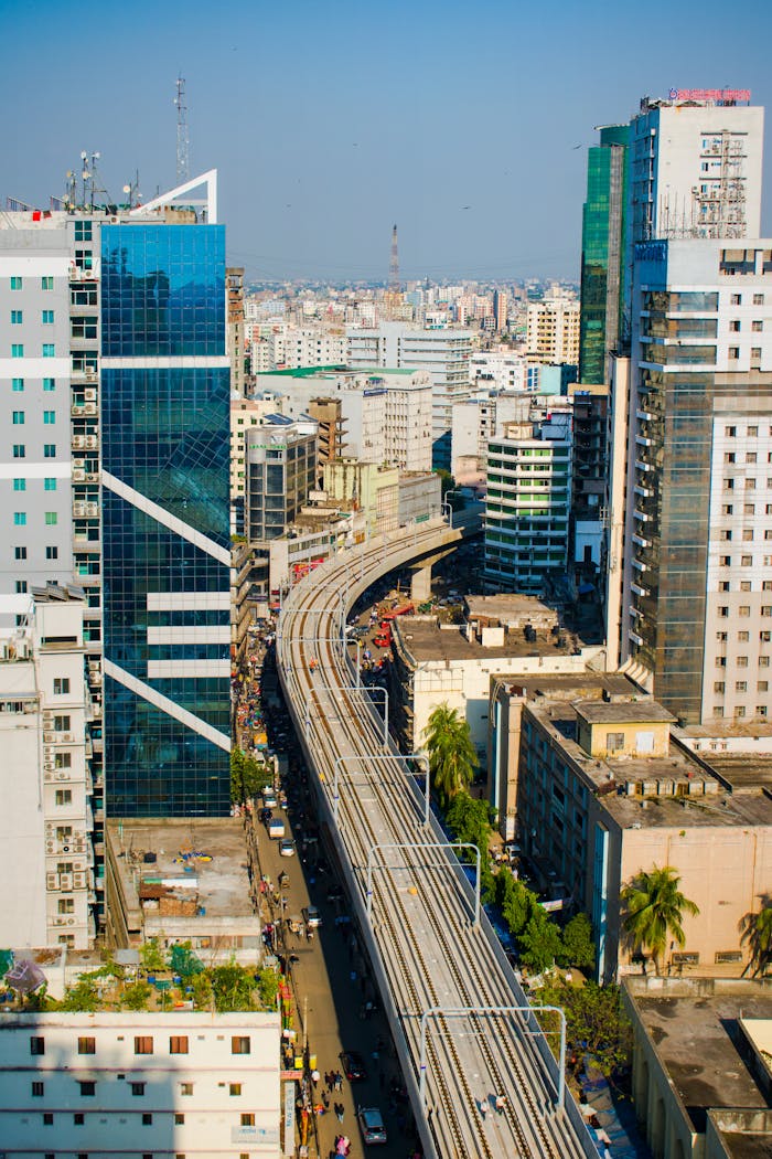 Aerial view of a railway cutting through a bustling urban cityscape, surrounded by towering skyscrapers.