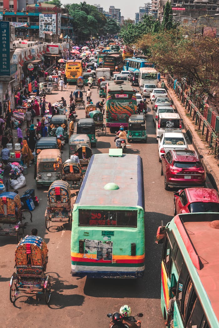 A crowded street in Dhaka, Bangladesh, captured from above showing bustling traffic and vibrant street life.