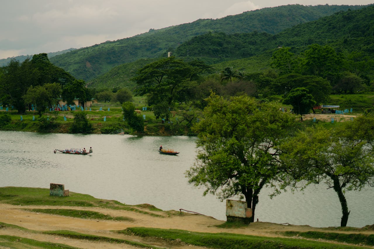 Serene river with boats against a backdrop of lush green hills and trees.
