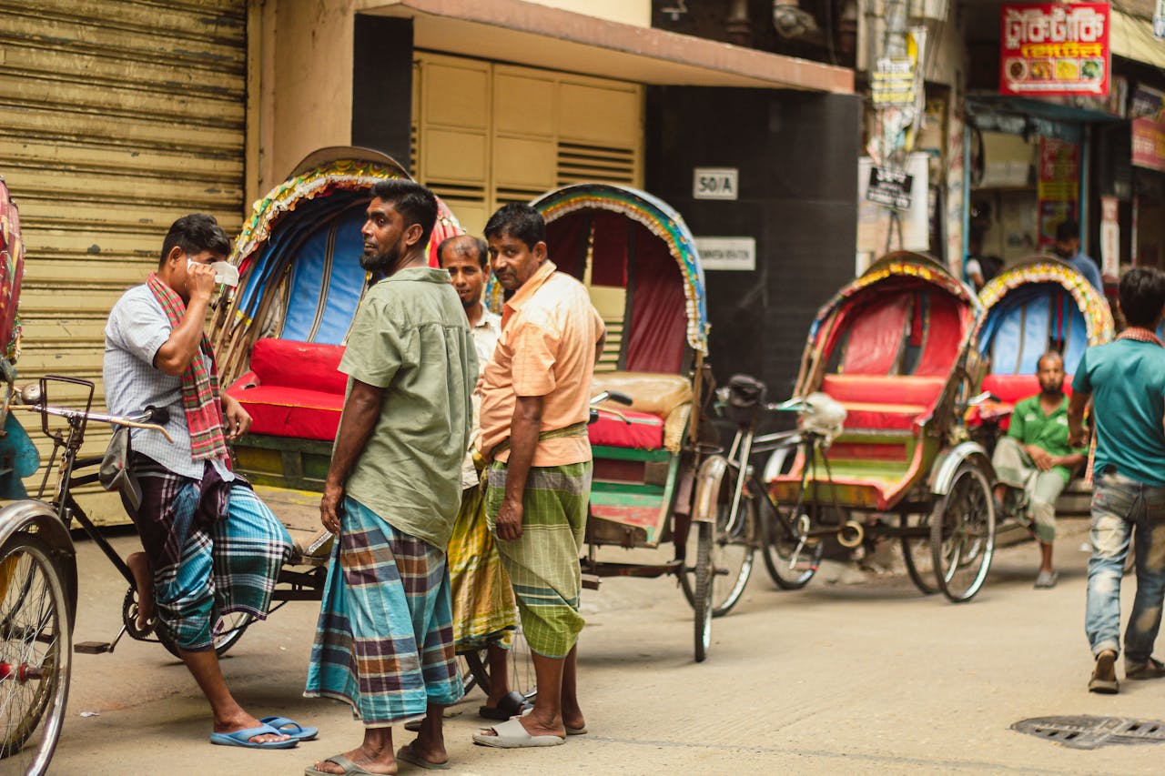 A vibrant street scene in Dhaka with rickshaw drivers waiting for customers.