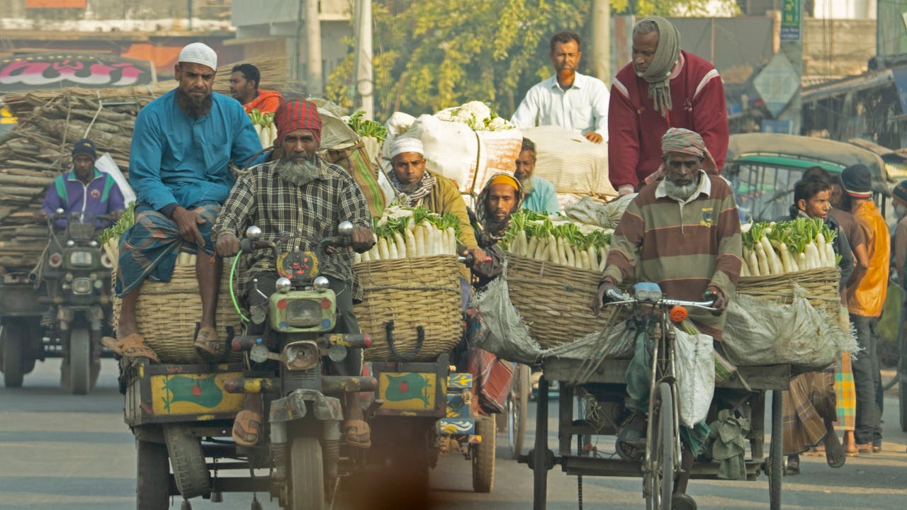 Street vendors in Bangladesh transporting fresh vegetables on bicycles and motorcycles.