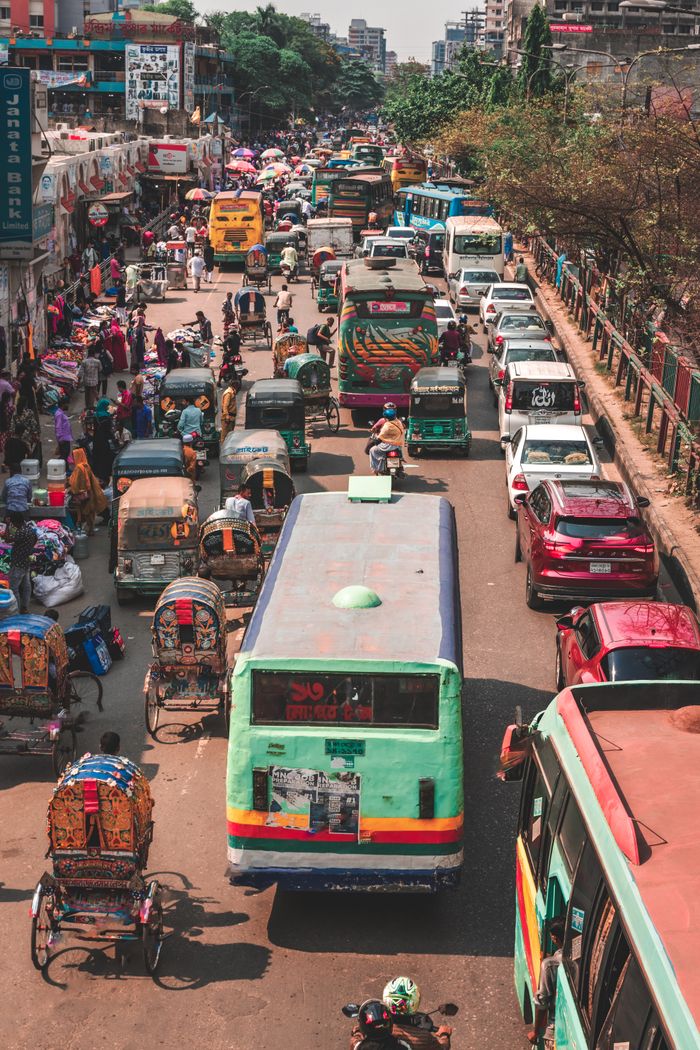 A crowded street in Dhaka, Bangladesh, captured from above showing bustling traffic and vibrant street life.